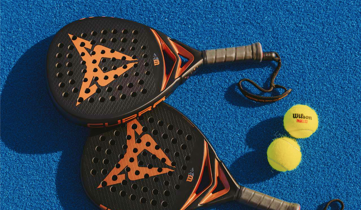 Zwei schwarzeCUPRA Padel-Schläger mit Logo und gelbe Tennisbälle auf blauem Spielfeld